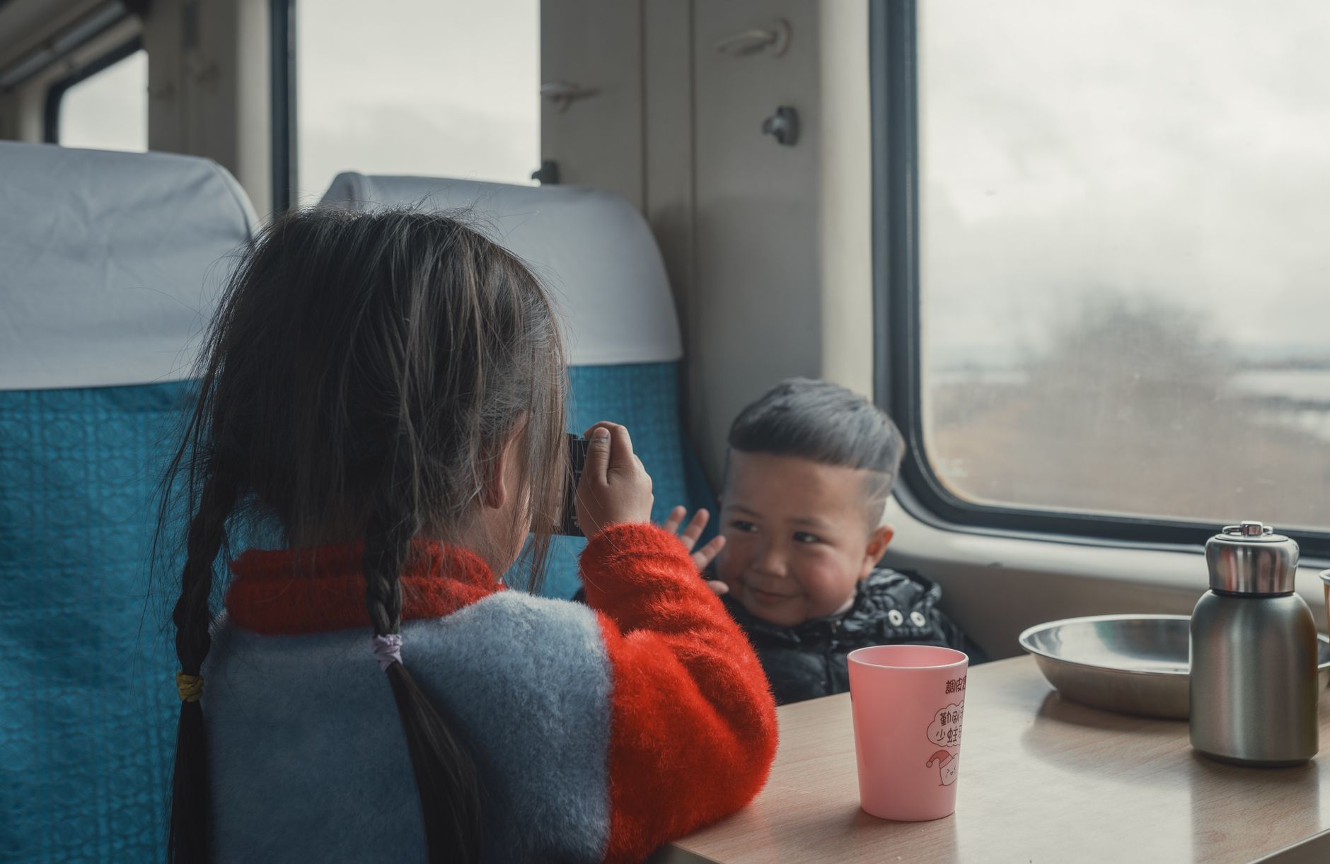 Two children playing inside a train cabin, capturing moments and enjoying the ride.