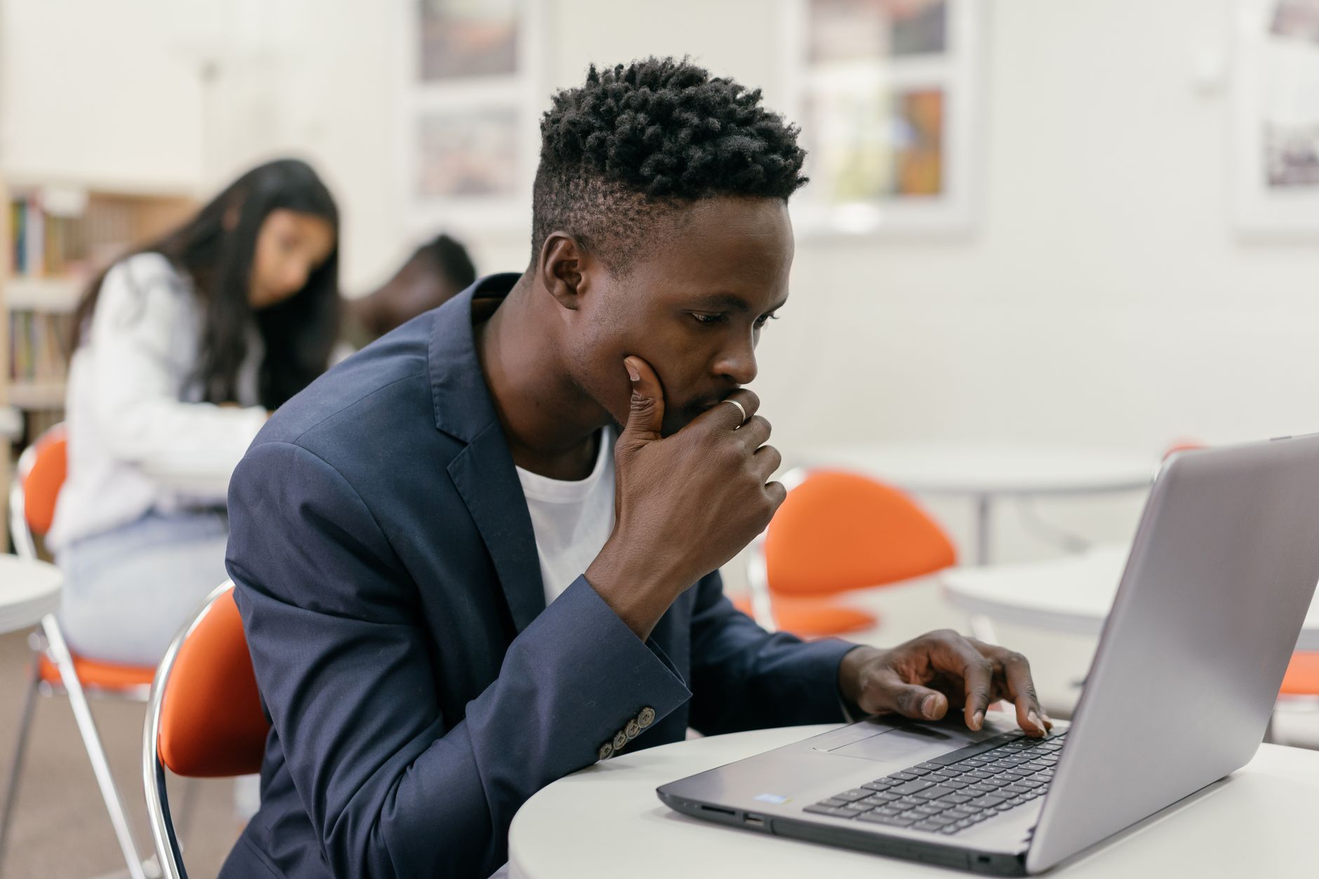 Focused student sitting at a laptop in a modern classroom setting.