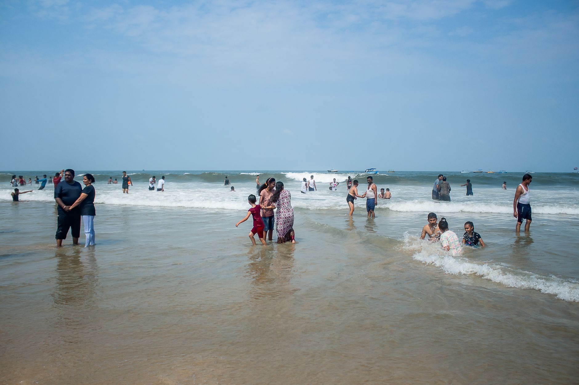 A vibrant scene of families enjoying a sunny day at the seaside, splashing in the waves.
