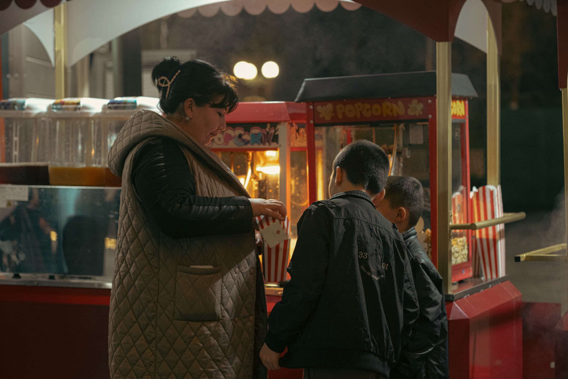 A woman and children buying popcorn at a night market stand in Uzbekistan.