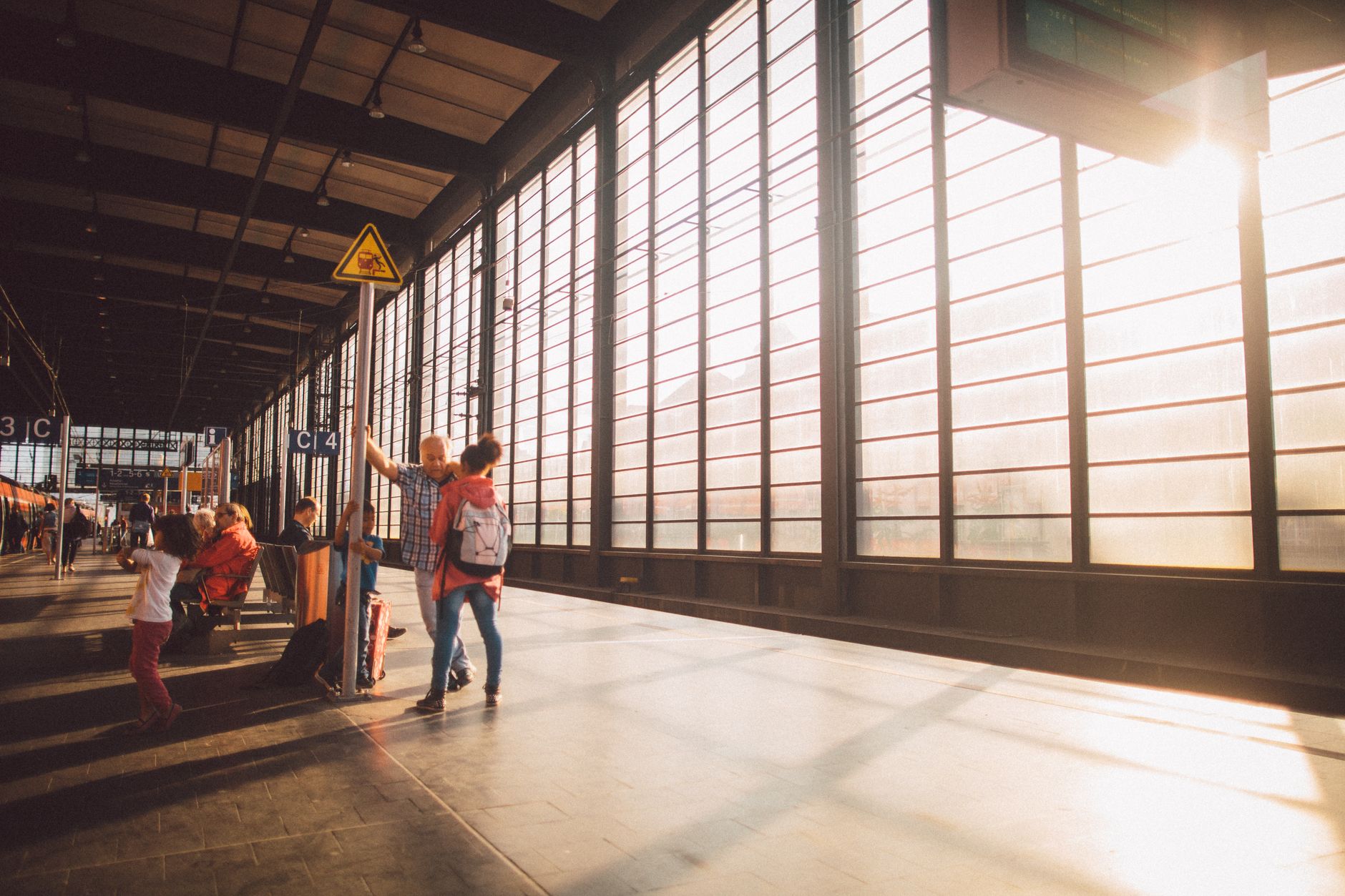 A vibrant moment at a Berlin train station with warm sunlight streaming through large glass windows.