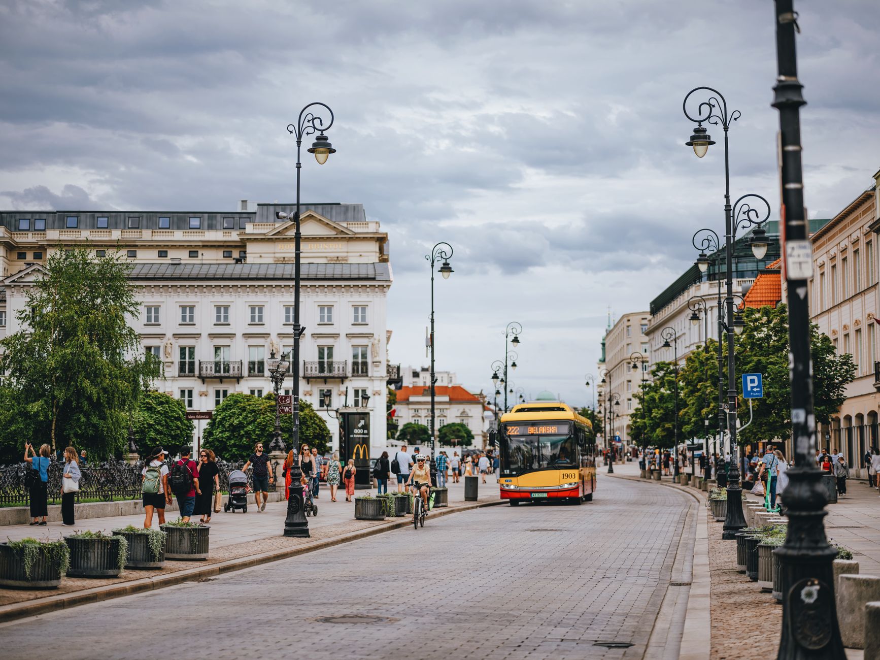 Bustling Warsaw street with modern bus and pedestrians, showcasing urban life.