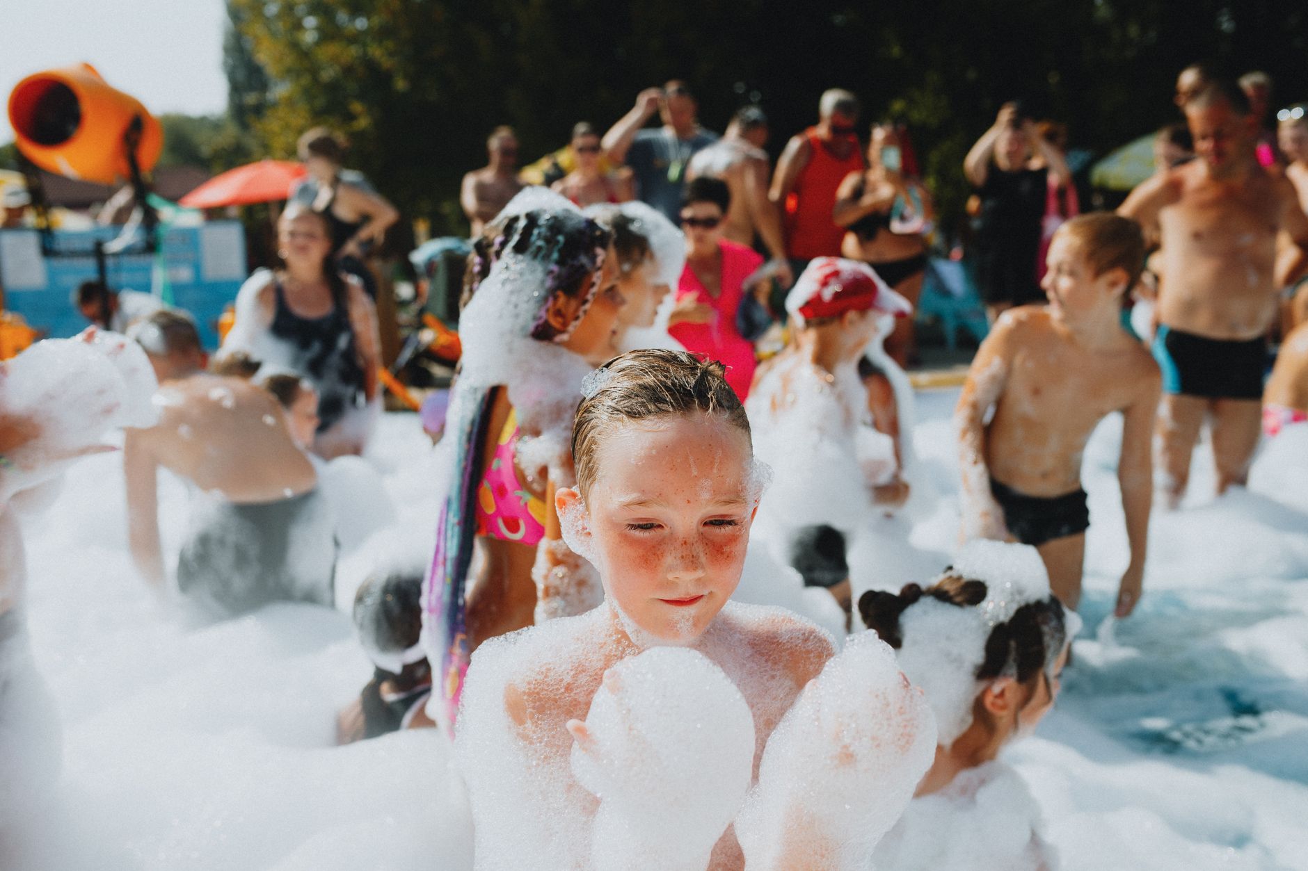 Children enjoy a refreshing foam party on a sunny day, surrounded by bubbles and laughter.