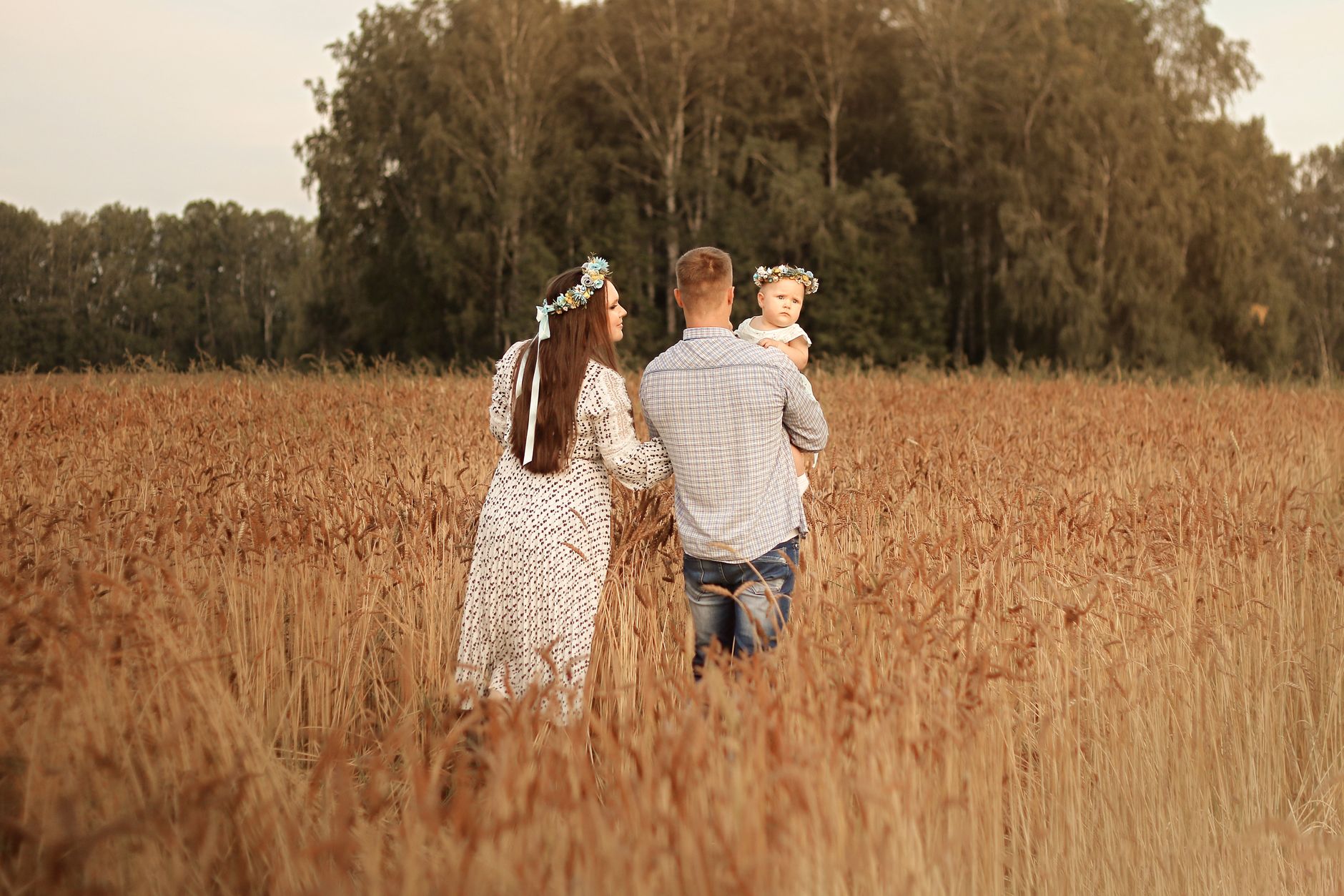 A family enjoying a stroll through a wheat field in the autumn countryside.