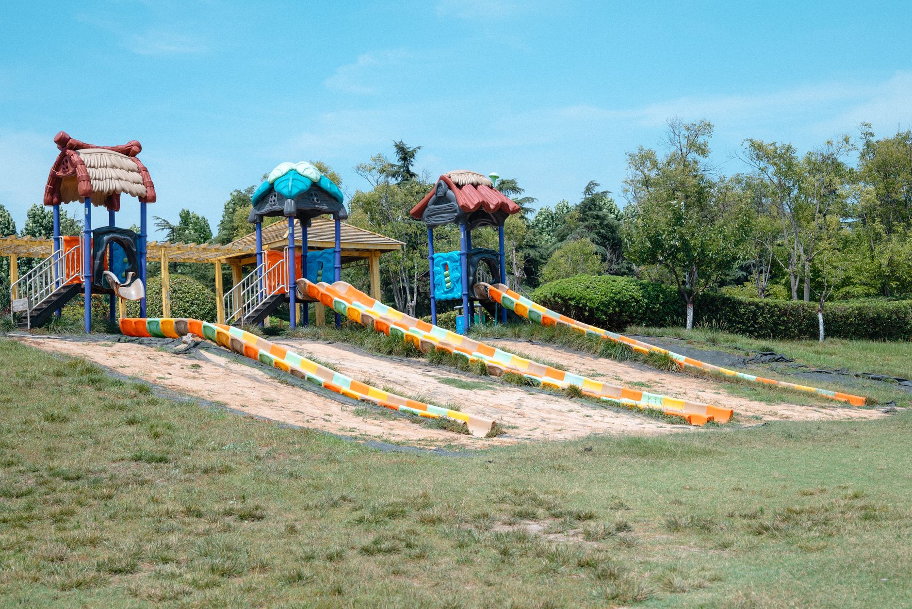 Colorful playground slides under a clear sky in an outdoor park setting.