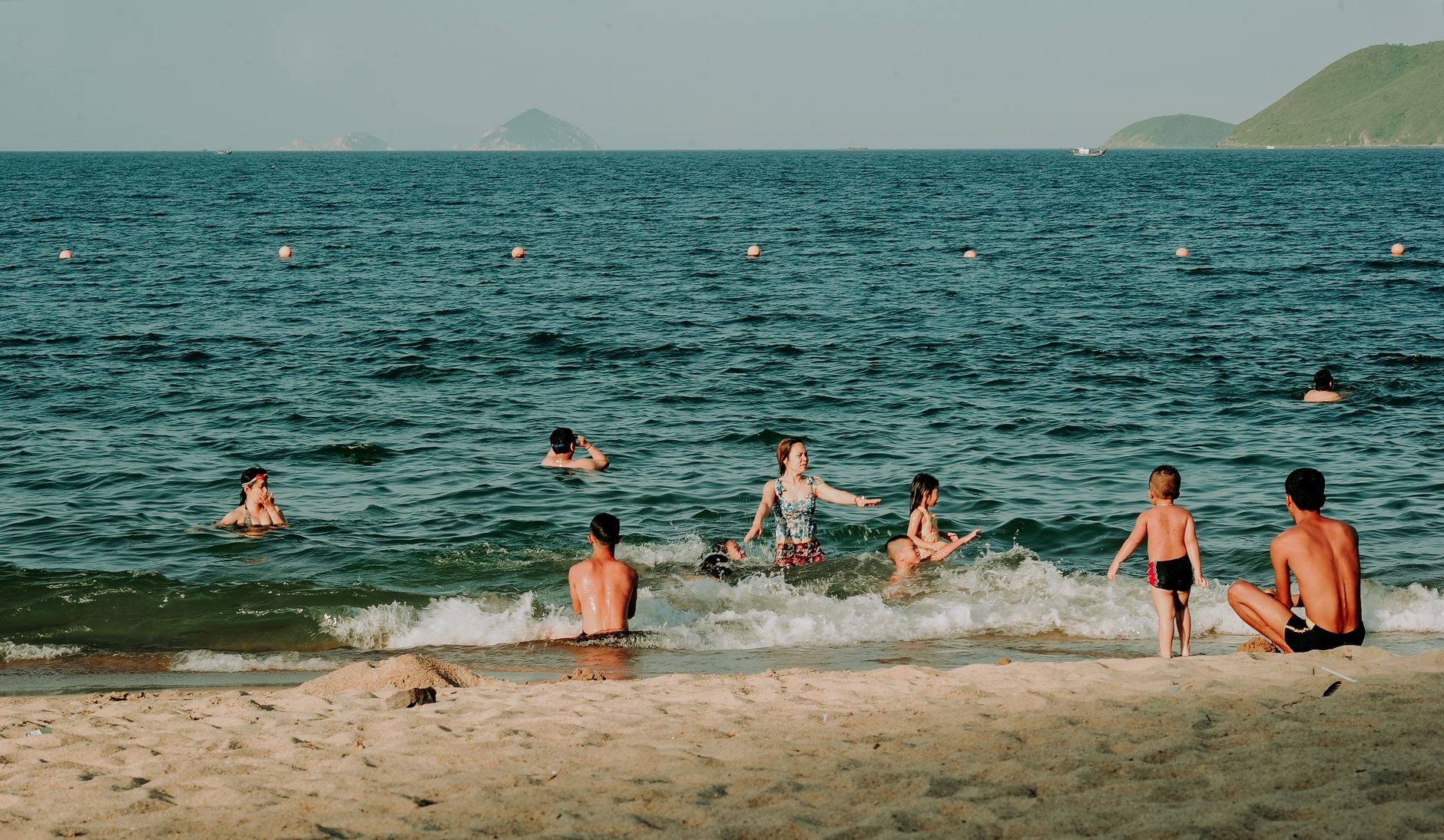 A joyful group of people swimming and relaxing on a sunny beach day.