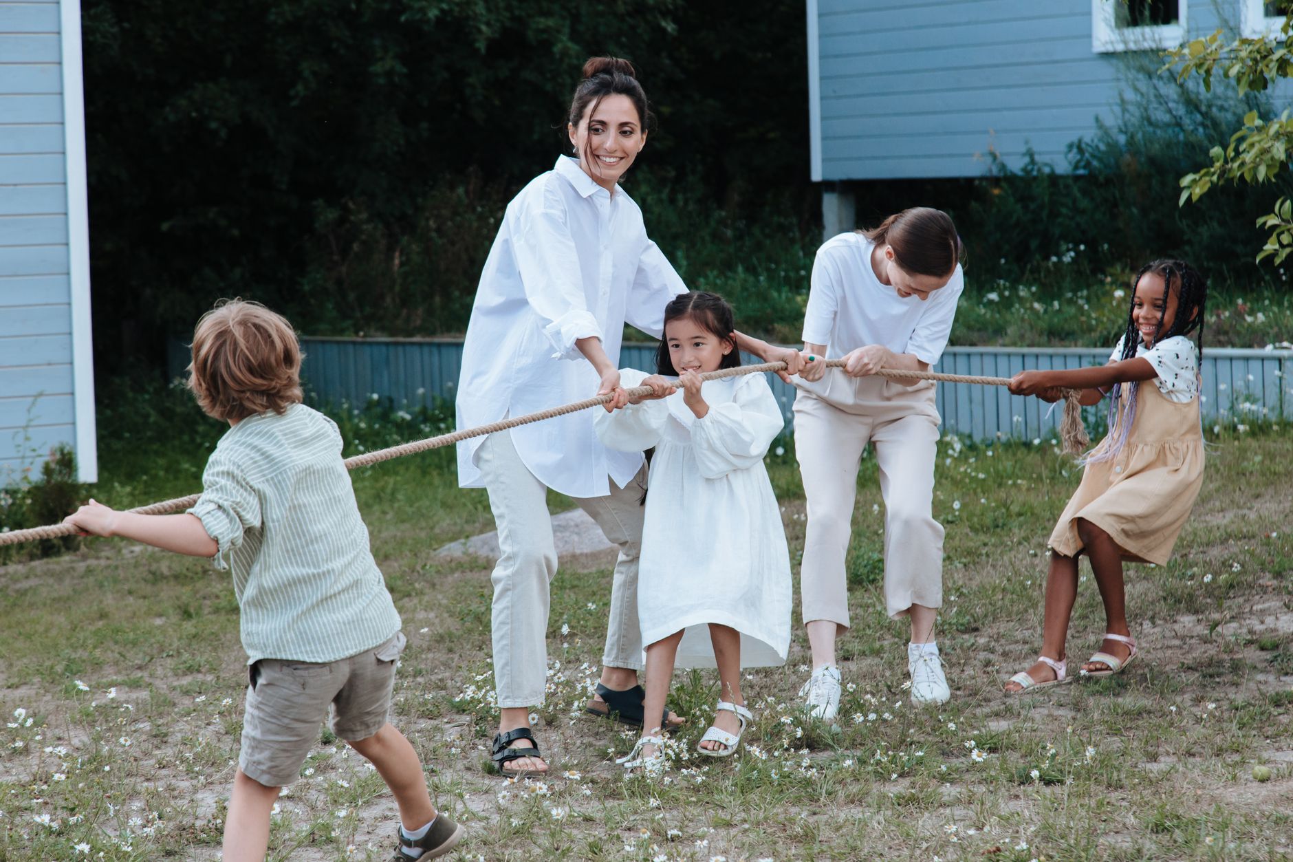 Family playing tug of war in backyard, showcasing teamwork and joy.