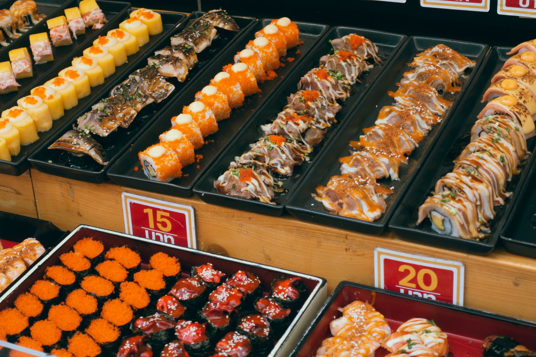 A colorful array of sushi platters at a buffet, showcasing assorted rolls and seafood delicacies.