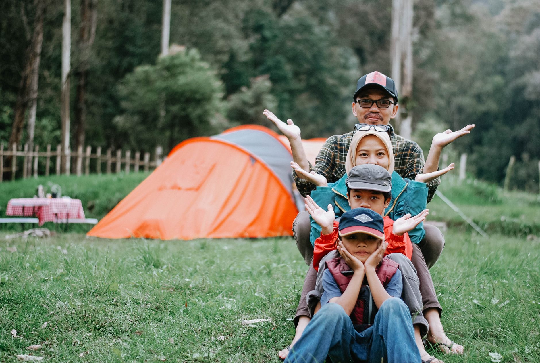 Family enjoying a fun camping trip with colorful tent in a lush green landscape.