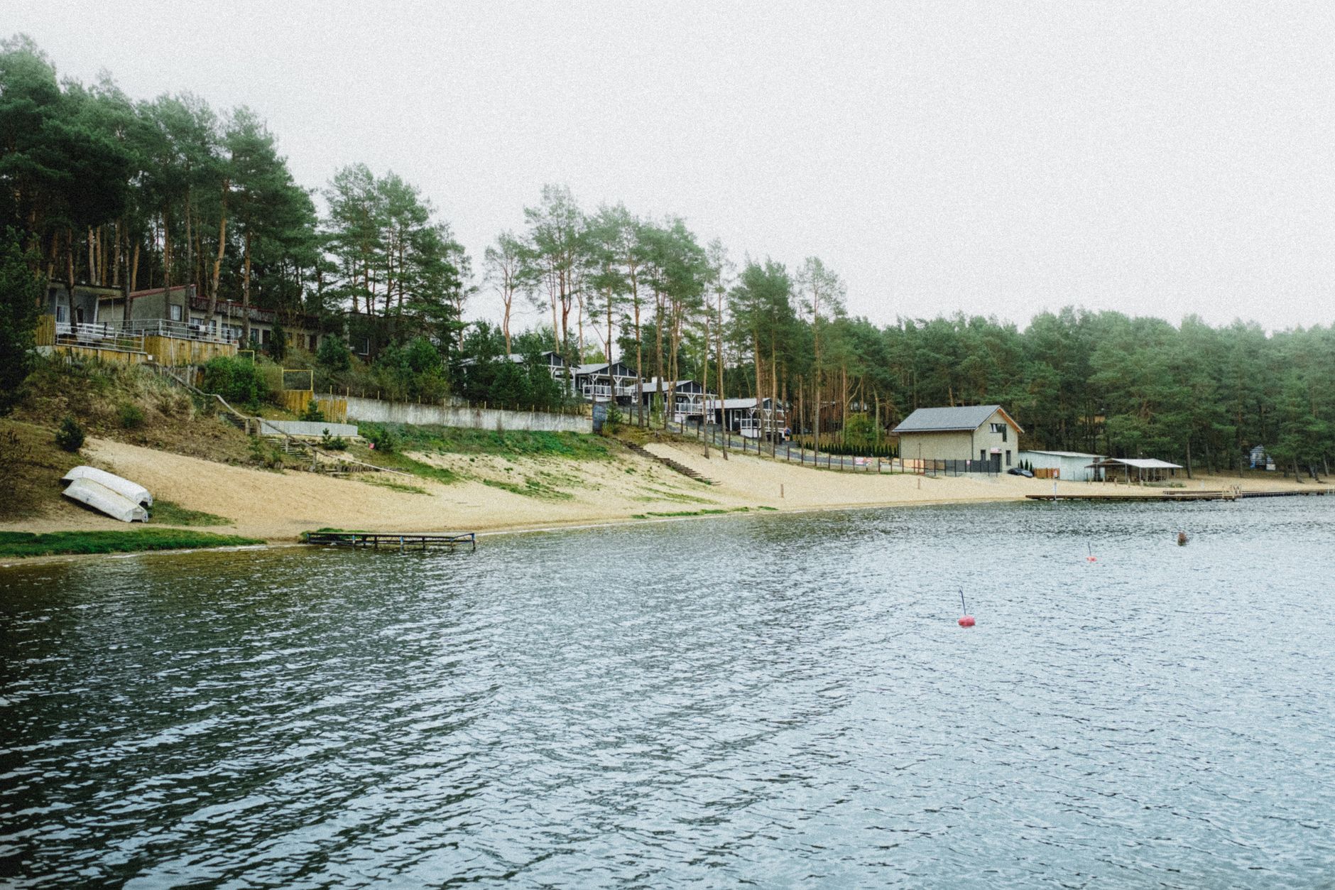 Peaceful lakeside scene in Ocypel, Poland with forest and cottages. Ideal for travel and nature themes.