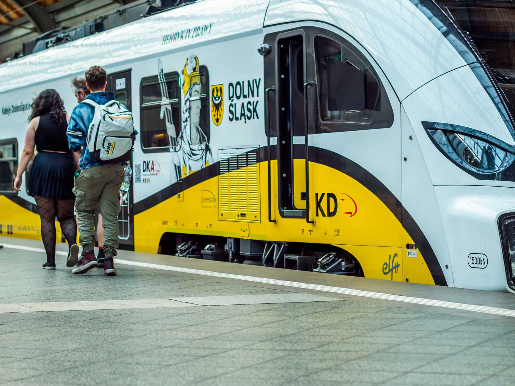 Passengers boarding a Dolny Śląsk train at a station platform, showcasing modern travel.