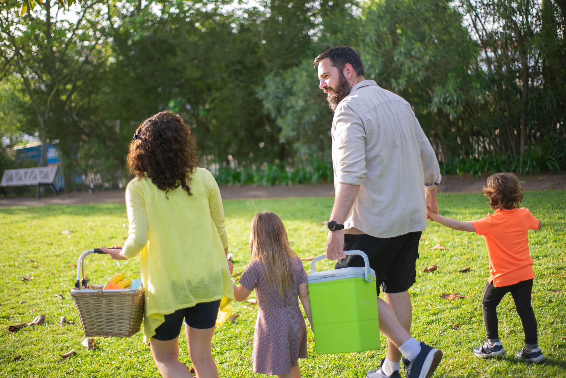 A family of four enjoys a picnic in a sunny park, capturing a joyful day outdoors.