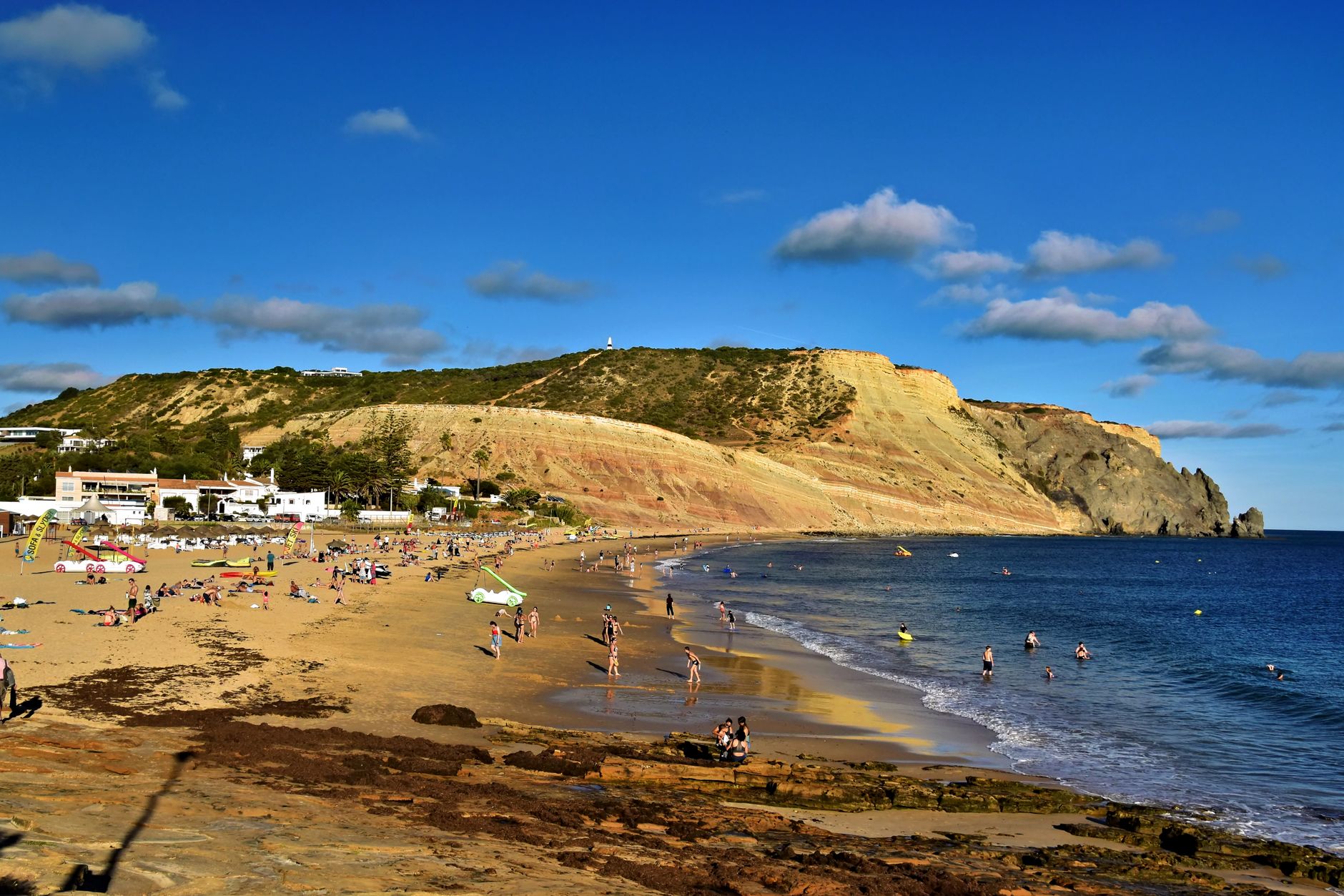 Scenic view of Luz beach in Algarve, Portugal with tourists enjoying a sunny day.