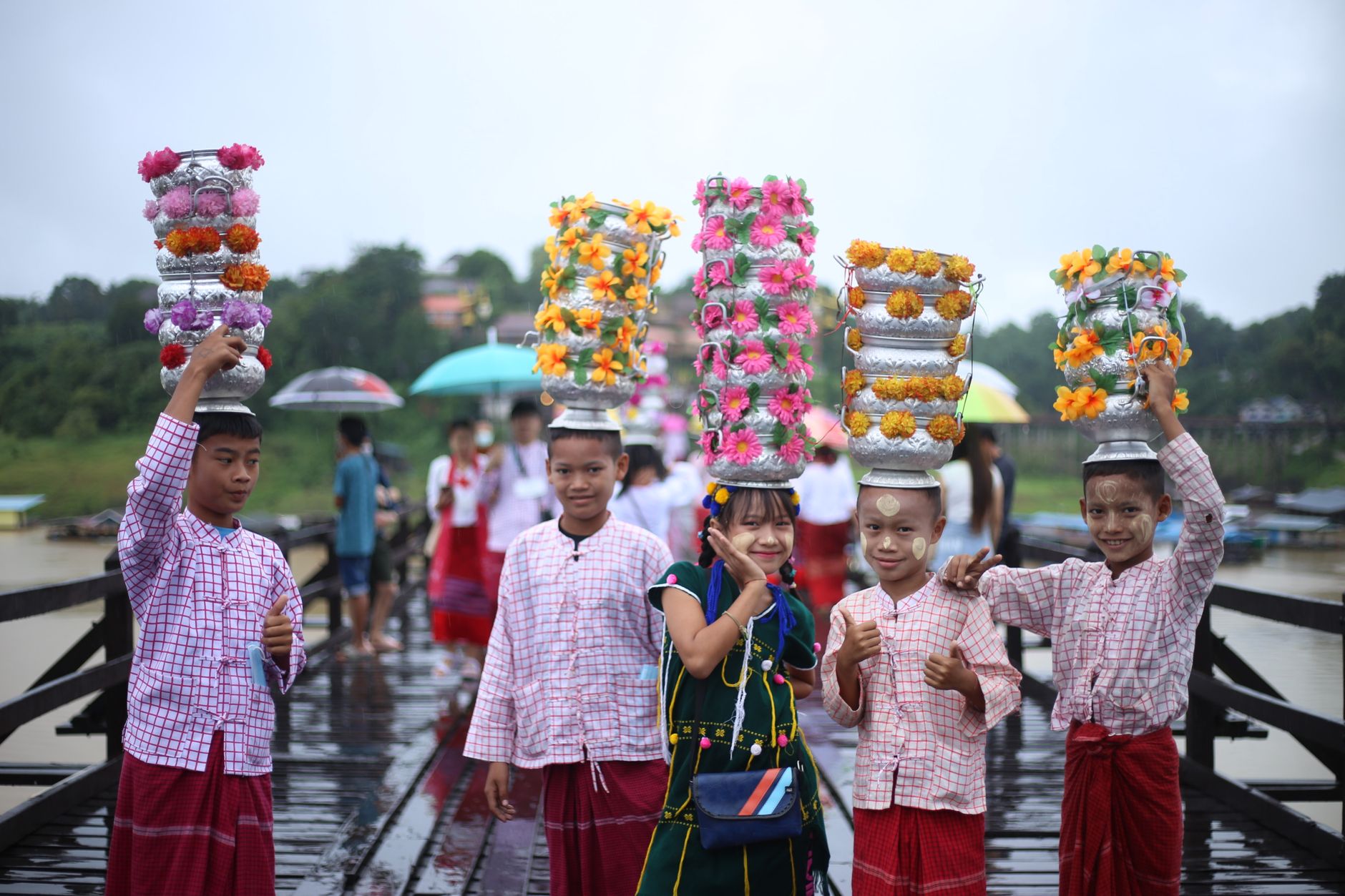 Children in traditional attire celebrating a vibrant festival with floral headpieces outdoors.