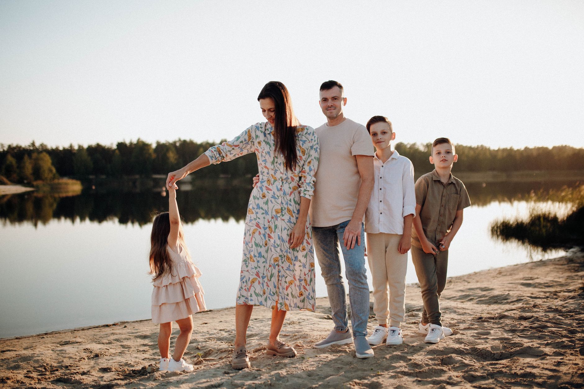 A family of five enjoys a serene lakeside vacation at sunset, capturing precious moments together.