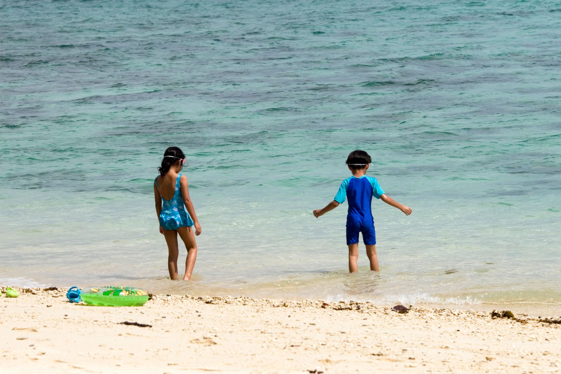 Two children playing at the beach on a bright summer day, enjoying the ocean waves.