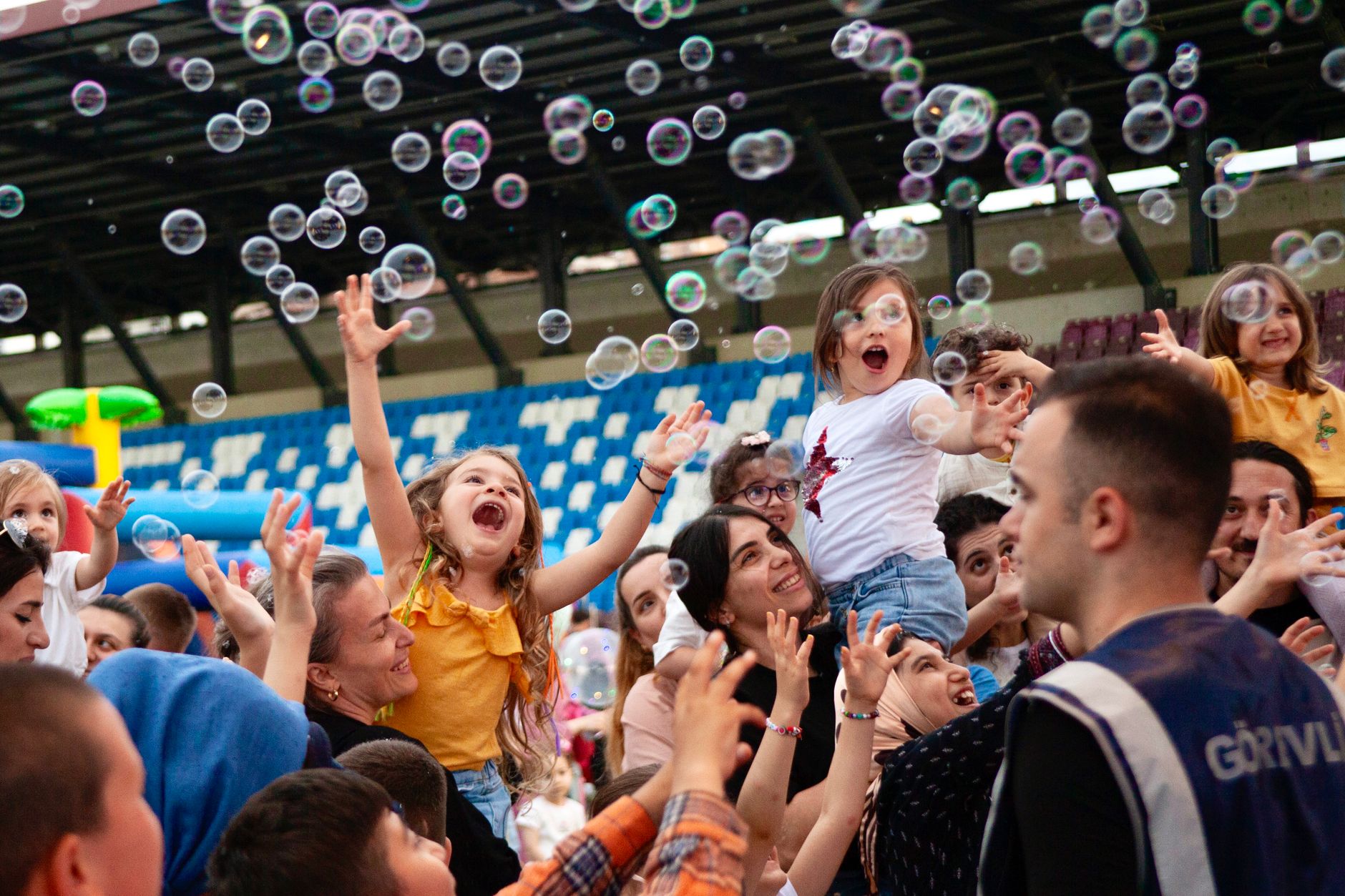 Children and adults joyfully engaging with bubbles at a vibrant outdoor event.