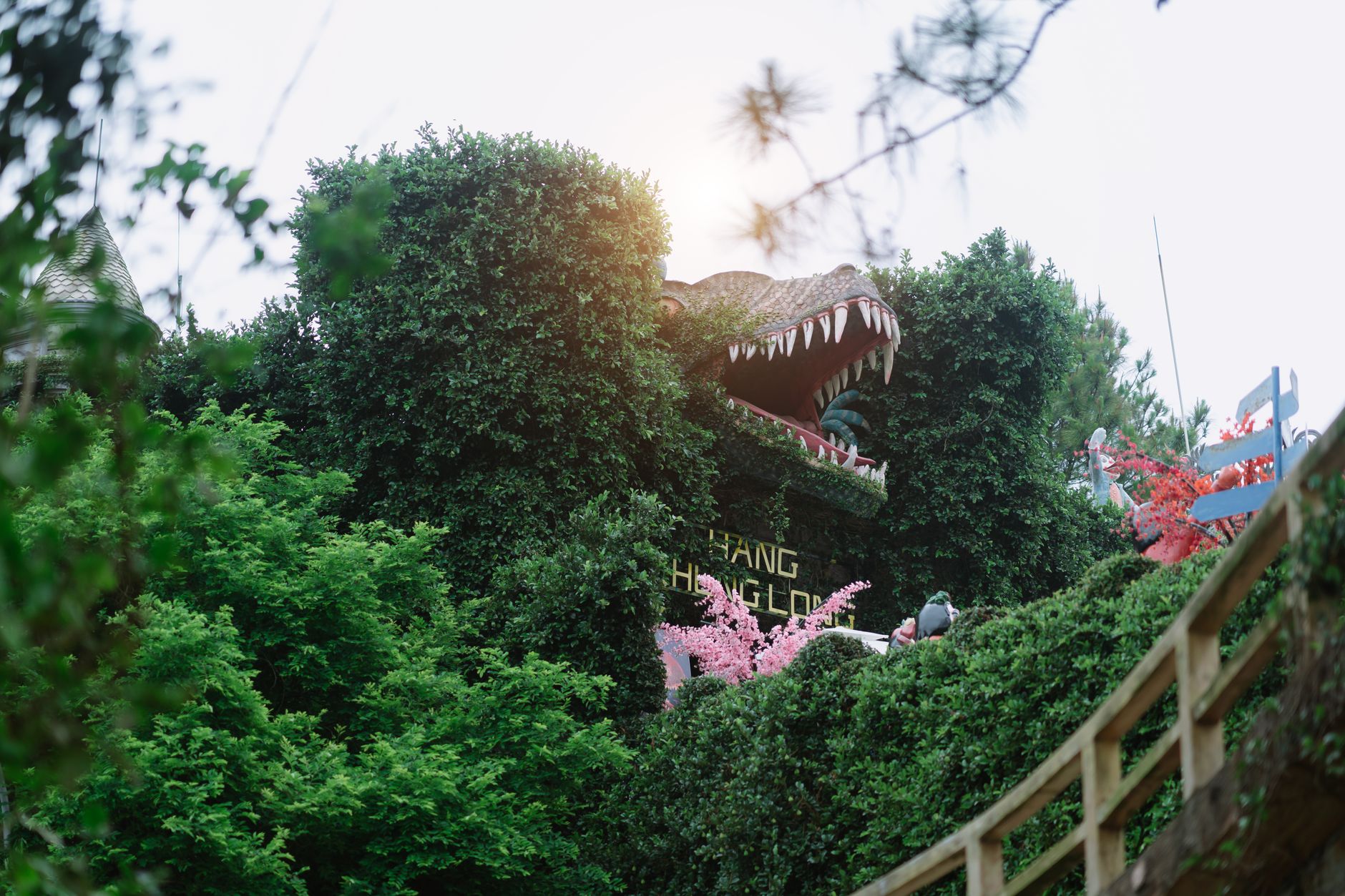 Giant dinosaur sculpture amidst lush greenery at a theme park. Perfect blend of amusement and nature.