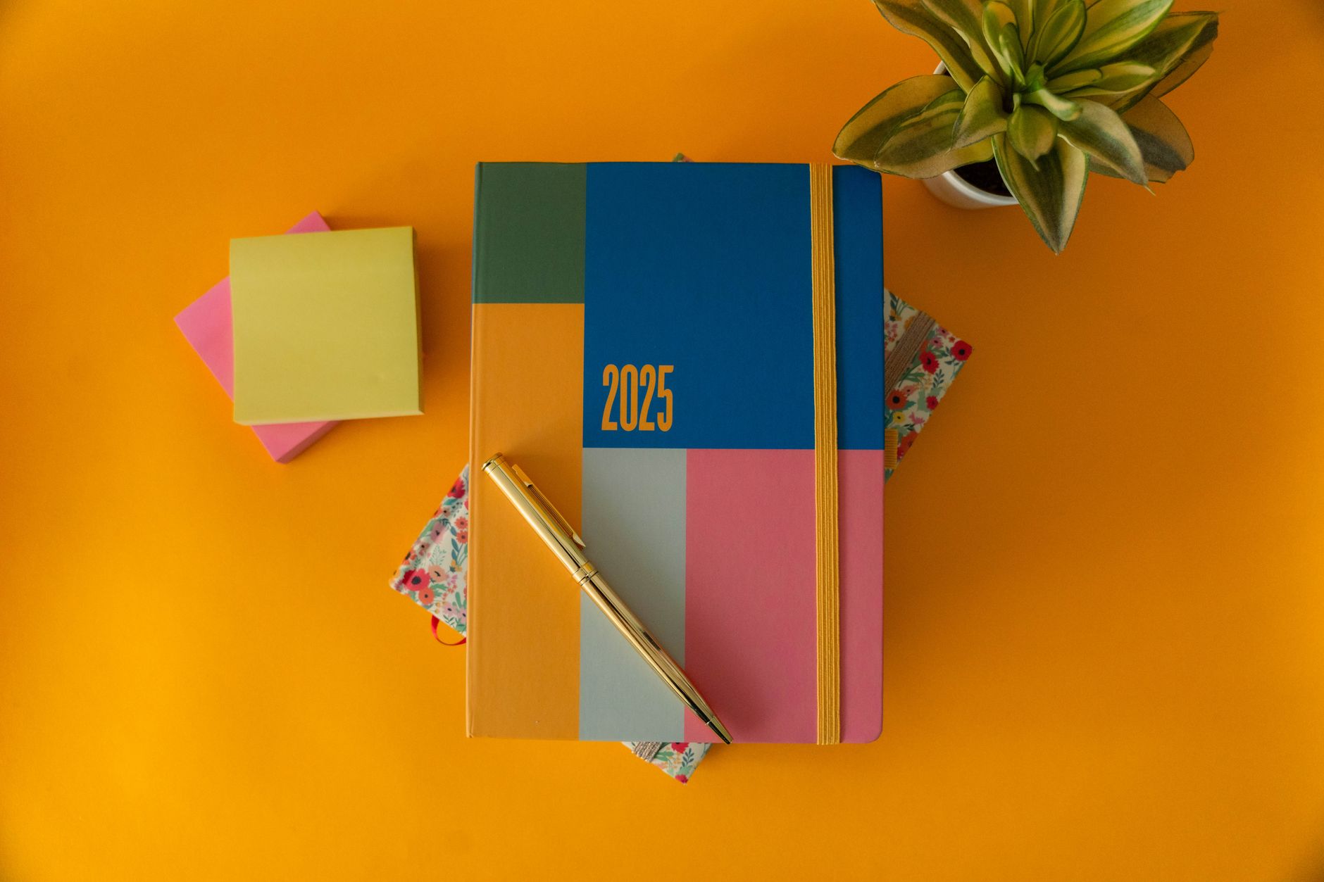A vibrant 2025 planner with a pen on a yellow background, perfect for organizing the year.