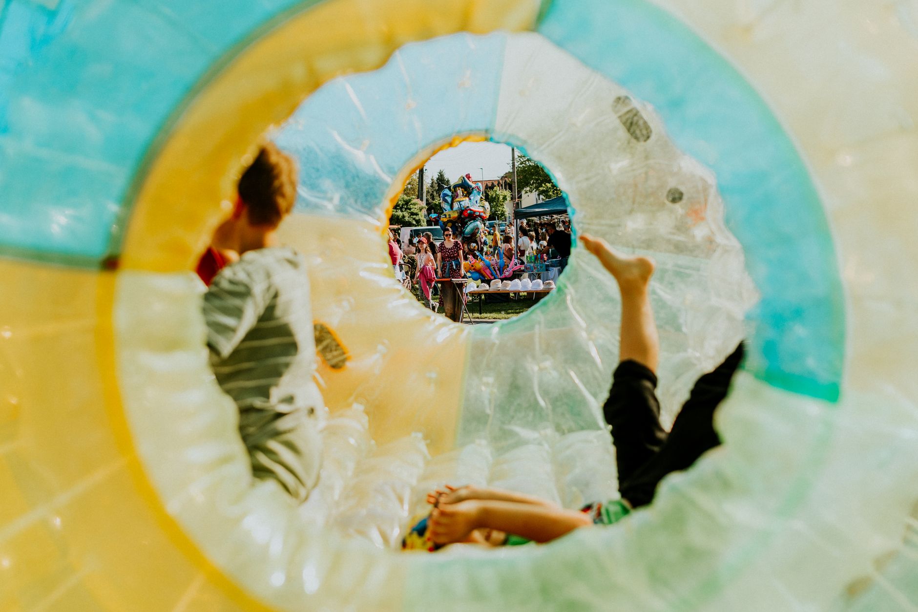 Children enjoying a summer festival inside a colorful inflatable structure, creating a lively and playful atmosphere.