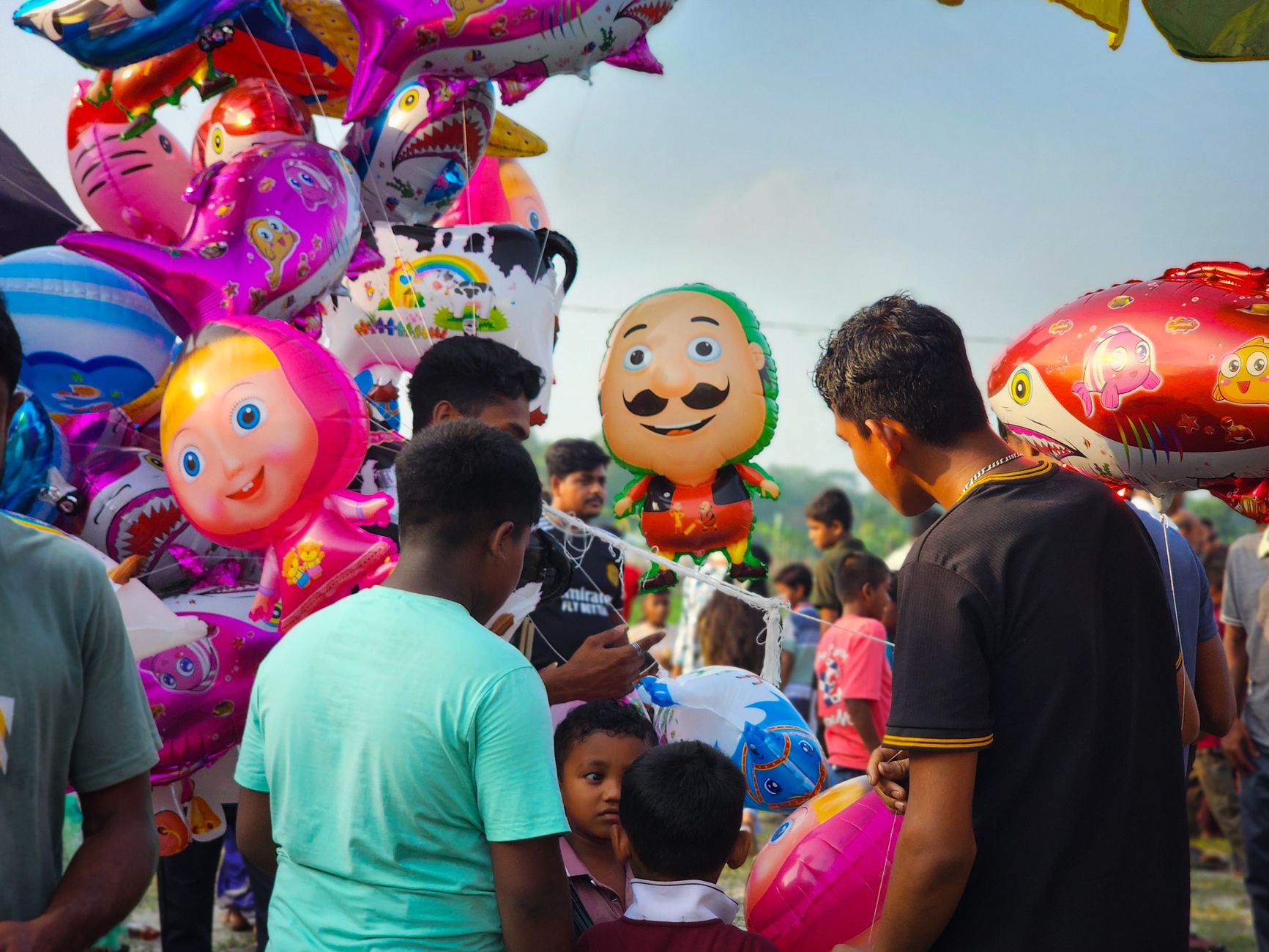 Vibrant outdoor festival with balloons and diverse crowd, showcasing joyful atmosphere.