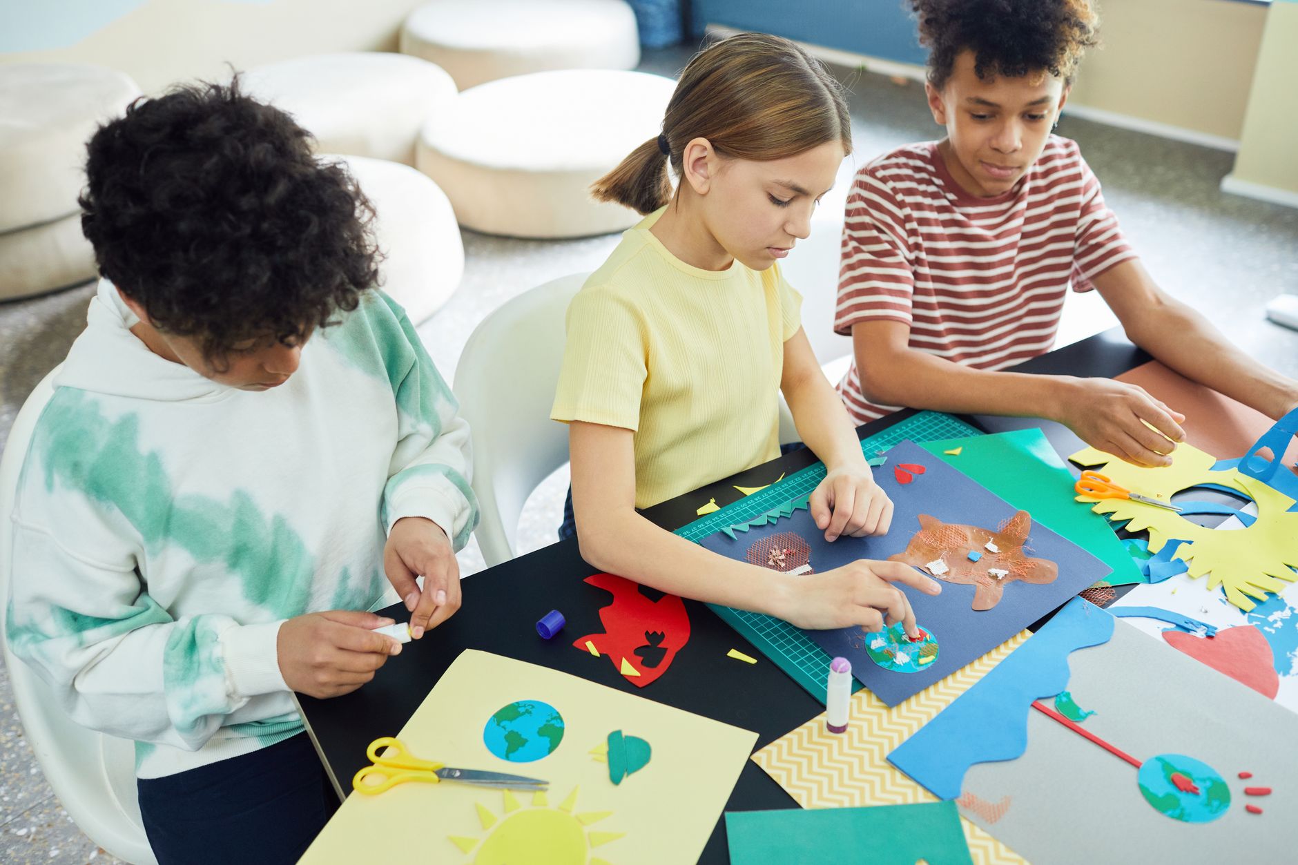 Children engaging in a creative crafting session with colorful art materials at a workshop table.