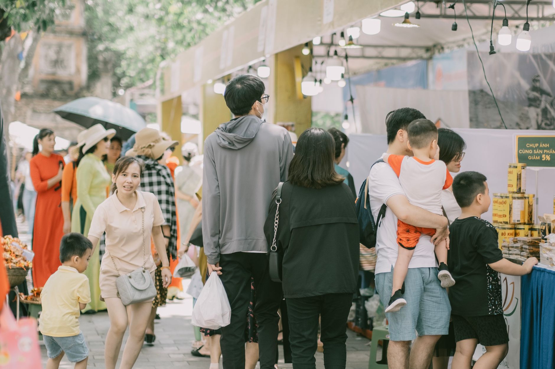A busy day at a lively street market with families shopping and exploring different stalls.