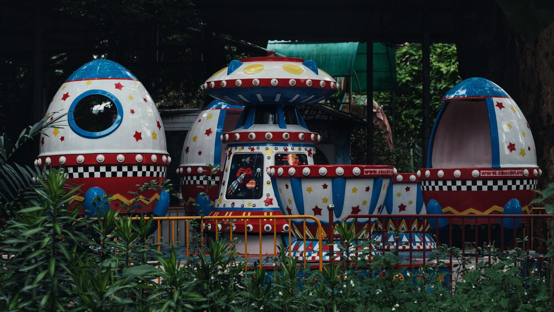 A colorful space-themed ride at an empty amusement park, featuring UFO shapes.