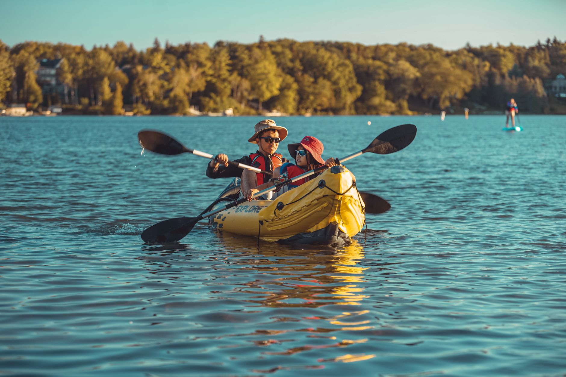 A father and daughter enjoy a kayaking adventure on a scenic lake, promoting leisure and bonding.