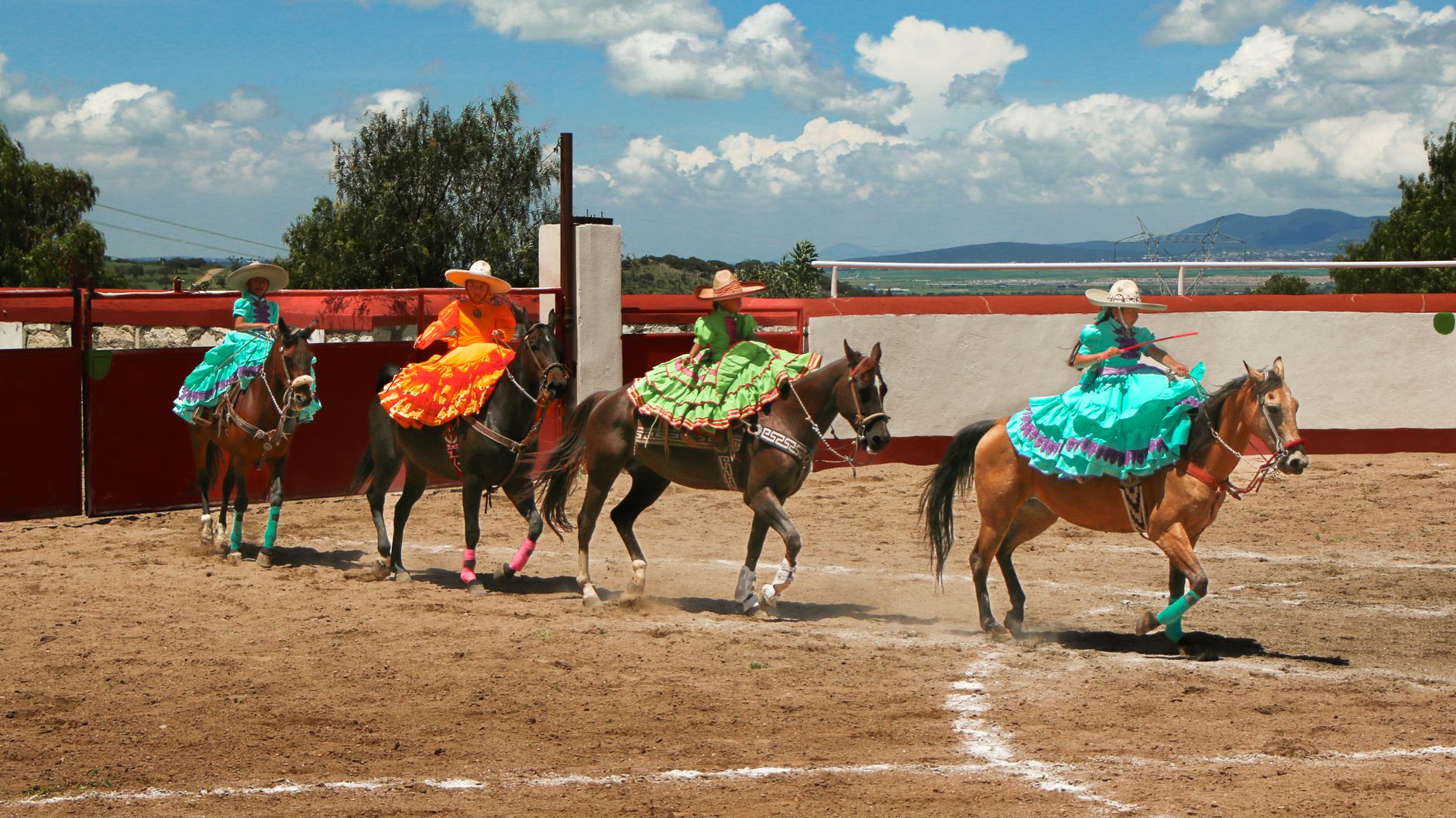 Vibrant Charrería performance featuring skilled riders in traditional attire with horses under a sunny sky.