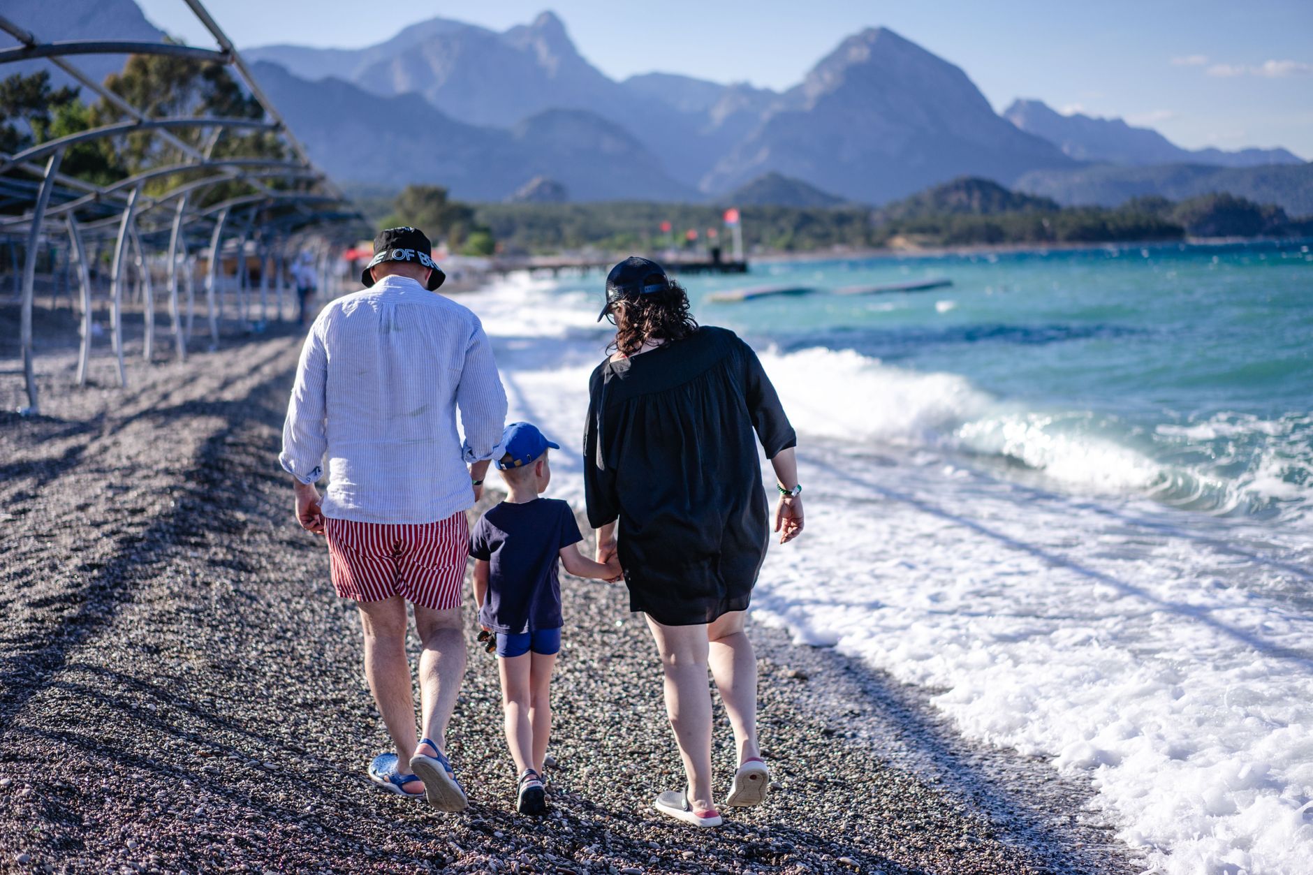 Family enjoying a sunny day at Kemer beach with mountains in the background.
