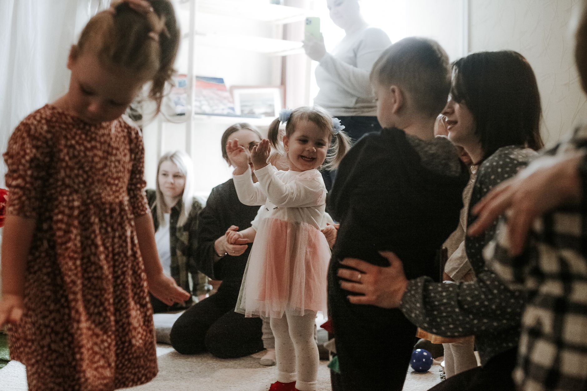 Happy children playing with family and friends during an indoor playdate, full of laughter and joy.