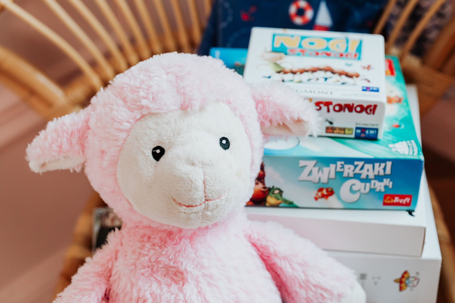 Close-up of a pink plush lamb alongside colorful board games, perfect for children's playrooms.