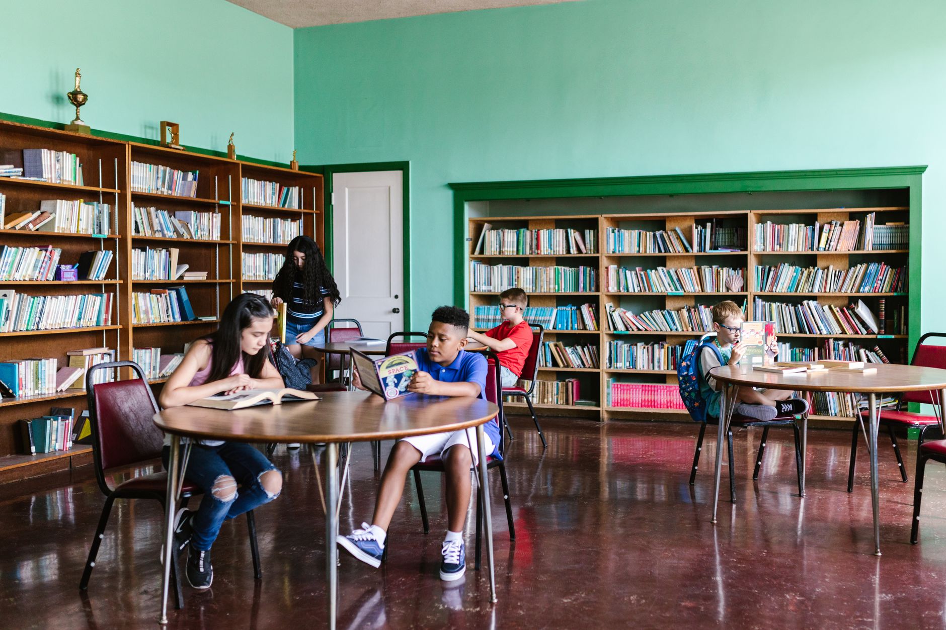 A diverse group of kids reading books in a library setting, fostering learning and togetherness.