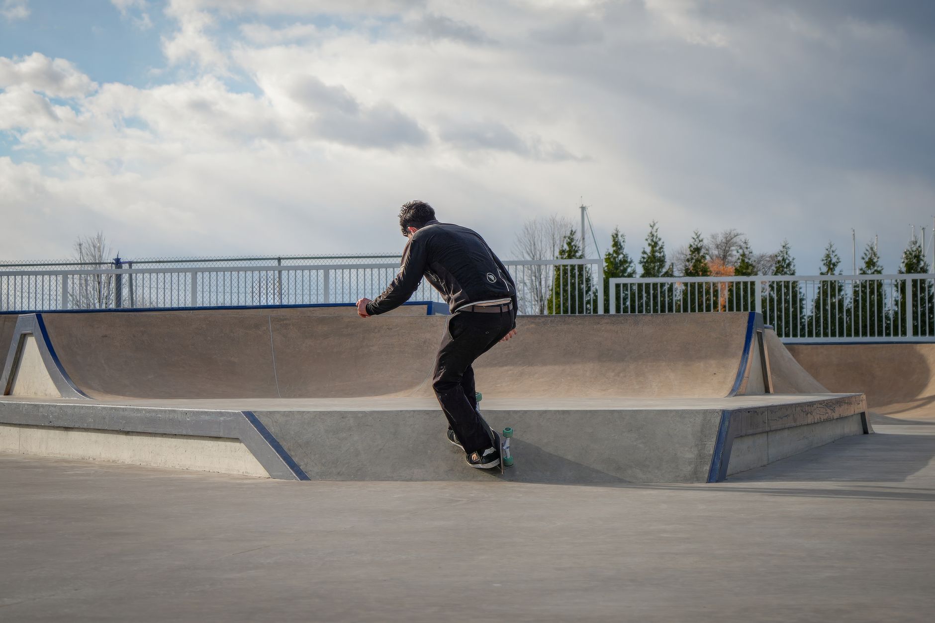 Adult skateboarder navigates a modern outdoor skatepark on a sunny day.