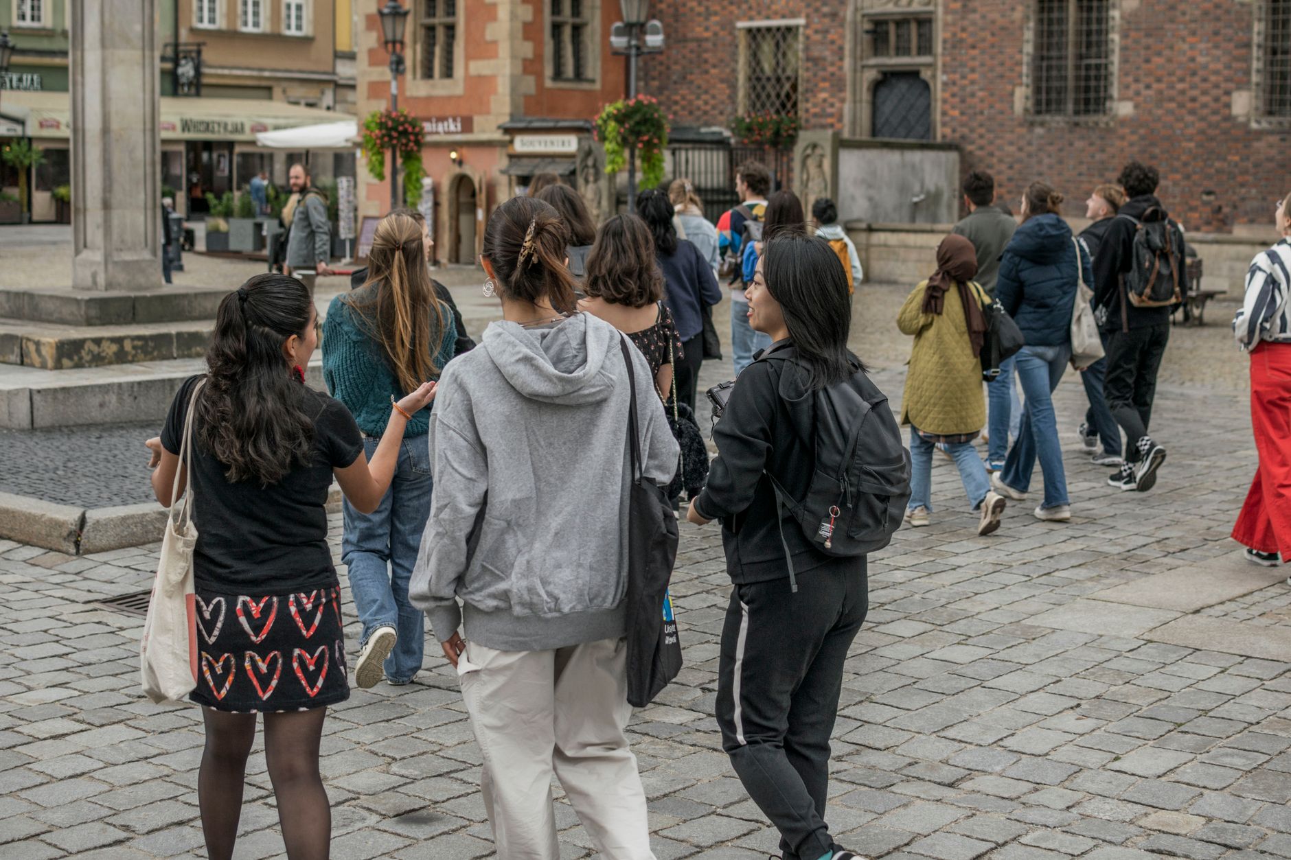 A diverse group of tourists walking through the historic streets of Wrocław, Poland.